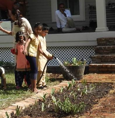 Inaya (in peach colored top) helps water the plants